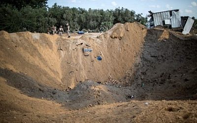 Palestinian militants of the Islamic Jihad movement arrive to inspect a crater on August 22, 2016 in Beit Lahia in the northern Gaza Strip, following an Israeli airstrike the day before that targeted Hamas positions in the Gaza Strip in response to a rocket fired from the Palestinian enclave hits the Israeli city of Sderot. 
AFP / Mahmud Hams