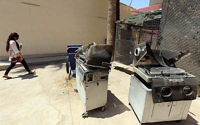 An Iraqi woman walks past burnt incubators standing outside Yarmuk hospital in west Baghdad on August 10, 2016 after an overnight fire tore through the maternity ward, killing at least 12 premature newborn babies. (SABAH ARAR/AFP)