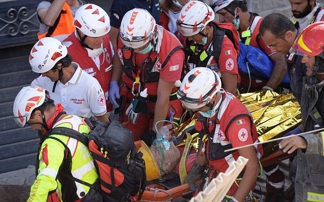 Rescue and emergency services personnel carry a survivor on a stretcher during search and rescue operations in Amatrice on August 24, 2016 after a powerful earthquake rocked central Italy.  (AFP PHOTO / FILIPPO MONTEFORTE)