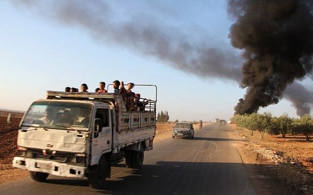 Syrians fleeing from the town of Souran, in northern Hama, drive past burning vehicles on September 1, 2016, after fighters from the Jund al-Aqsa Islamist Brigade took control of the town from Syrian government forces. (Omar haj kadour/AFP)