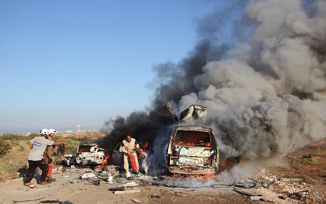 Syrian Civil Defense members, known as the White Helmets, search for survivors amid burning vehicles belonging to people fleeing in northern Hama, after they were reportedly targeted by a Syrian government forces air strike on September 1, 2016. (AFP PHOTO/Omar haj kadour)