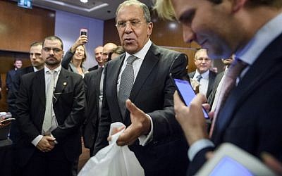 Russian Foreign Minister Sergei Lavrov hands out bottles of vodka to waiting journalists after meetings to discuss the Syrian crisis went late into the evening on September 9, 2016, in Geneva. (AFP PHOTO/FABRICE COFFRINI)
