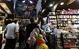 A poster of the Syrian President Bashar al-Assad and reading in Arabic: " Assad is with you forever" hangs above Syrians shopping at the Hamidiyeh popular market in the old part of the capital Damascus as they prepare for the Muslim Eid al-Adha holiday on September 11, 2016. (AFP PHOTO / LOUAI BESHARA)/