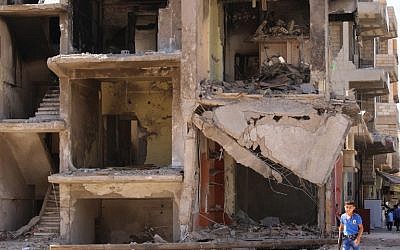 A Syrian boy carries a toy gun past a destroyed building in the northeastern Syrian city of Qamishli on September 13, 2016, as a truce brokered by Russia and the United States saw guns fall silent at sundown the previous night. (AFP/Delil Souleiman)