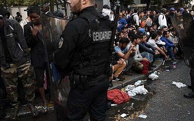 French gendarmes secure the area as migrants gather before being evacuated from a makeshift refugee camp set up between the metro stations of Jaures and Stalingrad, in Paris, on September 16, 2016. (AFP/Christophe Archambault)