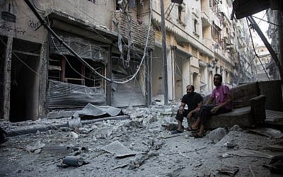 Syrians sit and look at the rubble following an air strike in Aleppo's rebel-controlled neighborhood of Karm al-Jabal, September 18, 2016. (AFP/Karam al-Masri)