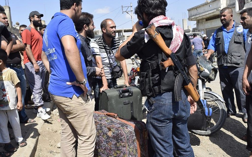 Syrian opposition fighters and their families wait to board a bus in the rebel-held Waer neighbourhood in the central city of Homs before crossing a Syrian army checkpoint during an evacuation operation on September 22, 2016. (AFP PHOTO/MAHMOUD TAHA)
