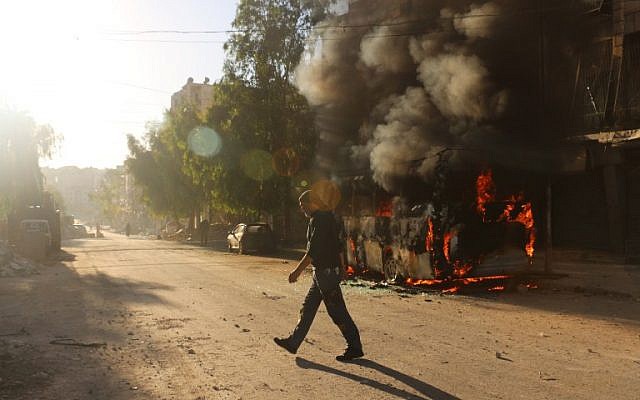 A Syrian man walks past a bus set ablaze following a reported air strike in the rebel-held Salaheddin district of Aleppo on September 25, 2016. (AFP/Ameer Alhalbi)
