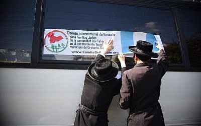 Members of an Orthodox Jewish community put a label from the 'International Rescue Committee for Jewish Families of the Lev Tahor Settlement' on the window of a bus in Guatemala city on September 25, 2016.  (AFP PHOTO / JOHAN ORDONEZ)