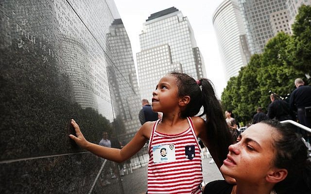 Bernadette Ortiz holds up her daughter Adriana as she looks for the name of her grandfather, fallen New York City police officer Edwin Ortiz, at a wall commemorating fallen officers on September 9, 2016 in New York City. (Spencer Platt/Getty Images/AFP)