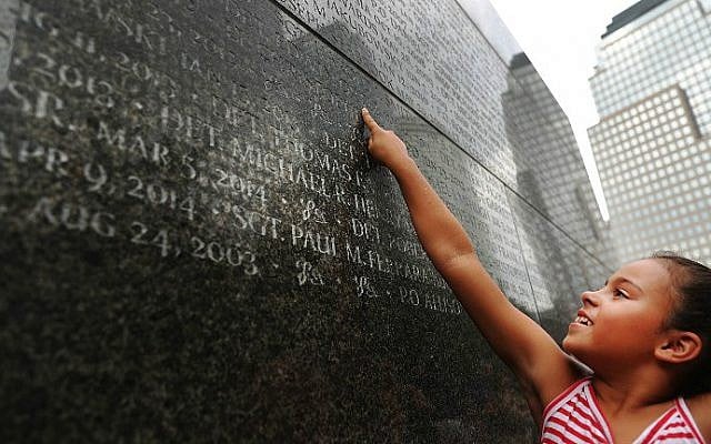 Gabriella Ortiz reaches up to point to the name of her grandfather, fallen New York City police officer Edwin Ortiz, at a wall commemorating officers who fell on or in the wake of the September 11, 2001 attacks, on September 9, 2016 in New York City. (Spencer Platt/Getty Images/AFP)