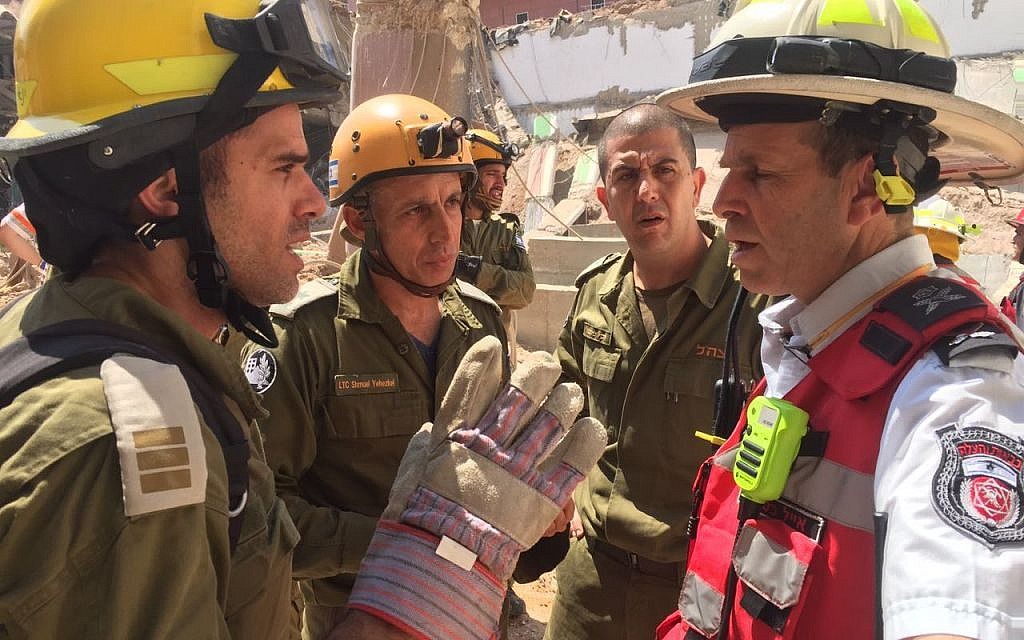 Representatives from the IDF Home Front Command's search and rescue unit speak with the head of the local fire department Eyal Caspi, right, at the site of a building collapse in the Ramat Hahayal neighborhood of Tel Aviv on September 5, 2016. (IDF Spokesperson's Unit)
