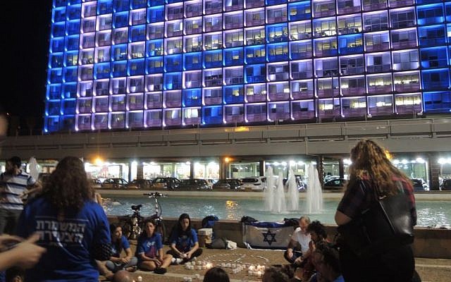 Young Labor activists sit in a circle to share memories and impressions of former president Shimon Peres in front of the Tel Aviv municipality building, whose lights flashed the words "Peace" and "Peres" on September 29, 2016. (Melanie Lidman/Times of Israel)