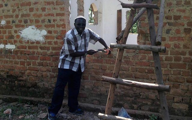 Rabbi Gershom Sizomu, leader of Uganda’s Jewish community, dismantling the old synagogue in Nabagoye. (Courtesy of Be’chol Lashon via JTA)