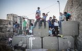 Palestinian children pose for a photo on top of cement blocks placed by the Israeli army in the East Jerusalem neighborhood of Ras al Amud, on October 21, 2015. (Hadas Parush/Flash90)