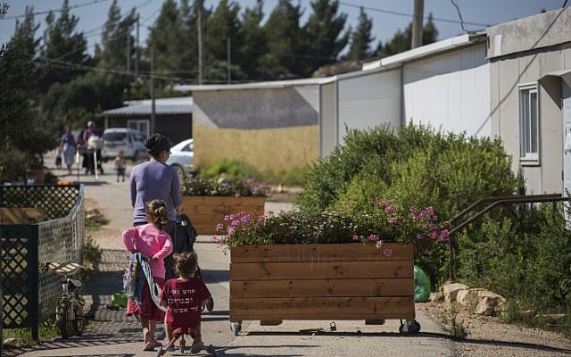 Families walk on a street in the Amona Jewish outpost in the West Bank, on July 28, 2016. (Hadas Parush/Flash90)