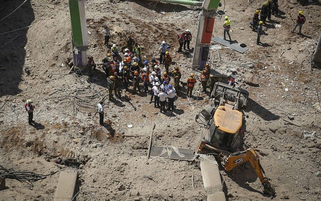 Rescue workers stand beside a tractor that is believed to have caused the collapse of a parking structure in the Ramat Hahayal neighborhood in northern Tel Aviv, killing two, on September 5, 2016. (Miriam Alster/Flash90)