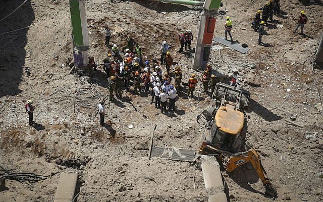 Rescue workers stand beside a tractor that is believed to have caused the collapse of a parking structure in the Ramat Hahayal neighborhood in northern Tel Aviv, killing two, on September 5, 2016. (Miriam Alster/Flash90)