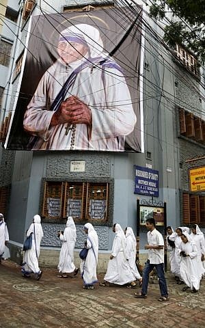 Nuns walk past a giant portrait of Mother Teresa hanging on the facade of the building of Missionaries of Charity, the order set up by Mother Teresa, in Kolkata, India, on September 3, 2016. (Bikas Das/AP Photo)