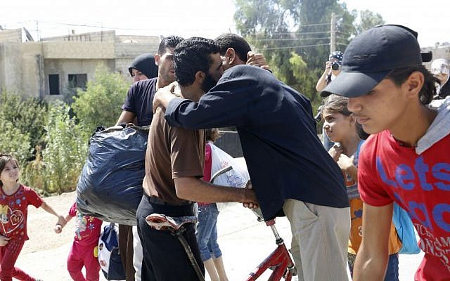 Men embrace while leaving the Moadamiyeh suburb of Damascus, Syria, on Friday, Sept. 2, 2016. (AP Photo)