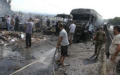 In this photo released by the Syrian official news agency SANA, Syrian security forces, emergency services and residents look at the remains of burned vehicles at the site of a bombing in Tartus, Syria, Monday, Sept. 5, 2016. (SANA via AP)