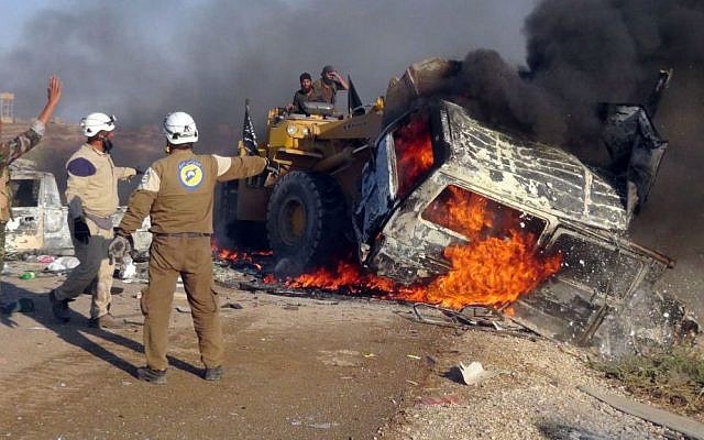 This photo provided by the Syria Press Center (SPC), an anti-government media group, shows rescue workers using a bulldozer to remove a burned van after airstrikes hit west of the town of Suran in Hama province, Syria, Thursday, Sept. 1, 2016, killing a dozen people. (Syria Press Center via AP)