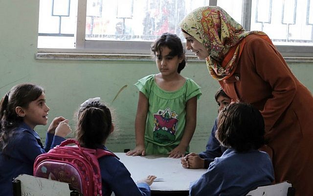 In this Thursday, Sept. 1, 2016 photo, a Jordanian teacher talks to Syrian refugee students at a school in Amman, Jordan. (AP Photo/Ahmad Alameen)