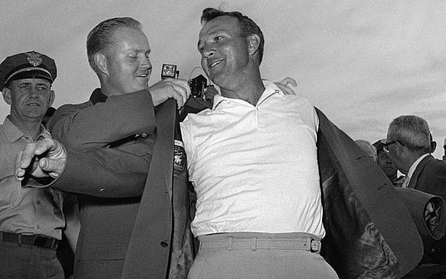 Arnold Palmer, right, slips into his green jacket with help from Jack Nicklaus after winning the Masters golf championship, in Augusta, Ga, April 12, 1964. (AP/File)