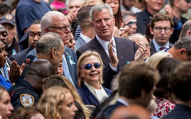 Democratic presidential candidate Hillary Clinton, center, accompanied by Sen. Chuck Schumer, D-New York, center left, Rep. Joseph Crowley, D-New York, second from left, and New York Mayor Bill de Blasio, center top, attends a ceremony at the Sept. 11 memorial, in New York, Sunday, Sept. 11, 2016. (AP Photo/Andrew Harnik)