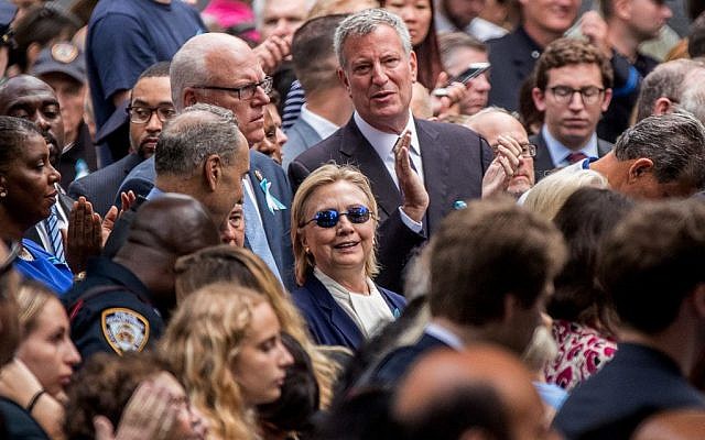 Democratic presidential candidate Hillary Clinton, center, accompanied by Sen. Chuck Schumer, D-N.Y., center left, Rep. Joseph Crowley, D-N.Y., second from left, and New York Mayor Bill de Blasio, center top, attends a ceremony at the Sept. 11 memorial, in New York, Sunday, Sept. 11, 2016. (AP Photo/Andrew Harnik)
