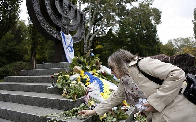 A woman lays a stone to Menorah monument in Babi Yar ravine where Nazi troops machine-gunned tens of thousands of Jews during WWII, Kiev, Ukraine, September 29, 2016. (AP/Sergei Chuzavkov)