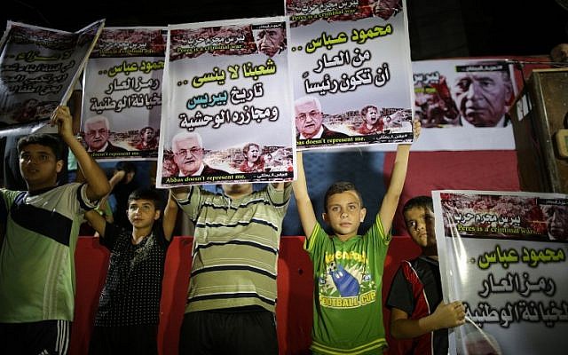 Palestinians hold placards during a protest in Gaza City on October 1, 2016 against president Mahmoud Abbas' participation in the funeral for Shimon Peres. The writing in Arabic reads: Mahmud Abbas shame on you to be president. (AFP/MAHMUD HAMS)