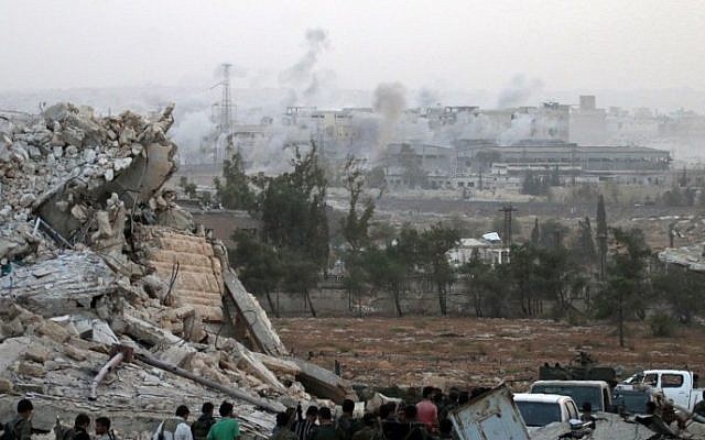 Syrian regime forces gather at the Kindi Hospital as smoke billows following aistrikes on Aleppo on October 2, 2016. (George Ourfalian/AFP)