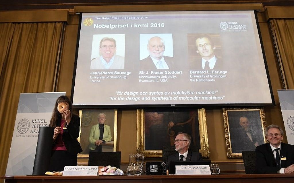 Professor of Physical Chemistry and Chairman of the Nobel Committee for Chemistry, Sara Snogerup Linse, left, uses a bagel to visualize her explanations during a press conference at the Royal Swedish Academy of Sciences in Stockholm on October 5, 2016. The winners of the 2016 Nobel Chemistry Prize, pictured behind her, are Jean-Pierre Sauvage, J Fraser Stoddart and Bernard L Feringa. (AFP / JONATHAN NACKSTRAND)