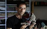 Israeli shoe designer Kobi Levi poses in his workshop with one of his shoe creations called "Miao" in Tel Aviv, on October 5, 2016. (AFP PHOTO / THOMAS COEX)