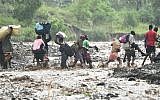 Haitian people cross the river La Digue in Petit Goave where the bridge collapsed during the rains of the Hurricane Matthew, southwest of Port-au-Prince, October 5, 2016. (AFP PHOTO / HECTOR RETAMAL)