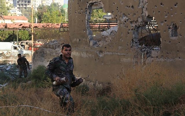 A Syrian regime soldier carries home-made bombs during an advance into Aleppo's rebel-held Bustan al-Basha neighborhood on October 6, 2016. (AFP/George Ourfalian) A Syrian regime soldier carries home-made bombs during an advance into Aleppo's rebel-held Bustan al-Basha neighborhood on October 6, 2016. (AFP/George Ourfalian)