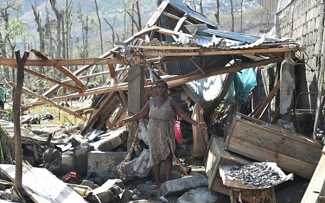 A woman stands in front of her house that was destroyed in hurricane Matthew, in Jeremie, in western Haiti, on October 7, 2016. (AFP PHOTO / HECTOR RETAMAL)