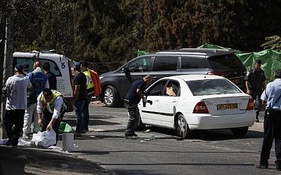 An Israeli forensic policeman collects evidence from a car belonging to an assailant after a shooting attack near the Israeli police headquarters in Jerusalem on October 9, 2016. (AFP/AHMAD GHARABLI)