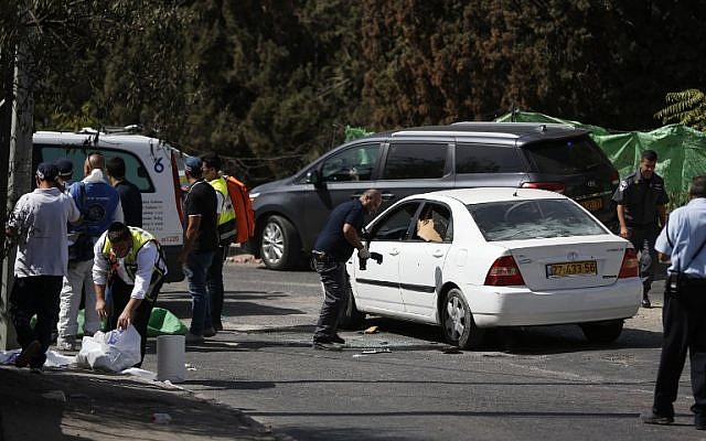 An Israeli forensic policeman collects evidence from a car belonging to an assailant following a shooting attack near the Israeli police headquarters in Jerusalem on October 9, 2016. (AFP/AHMAD GHARABLI)