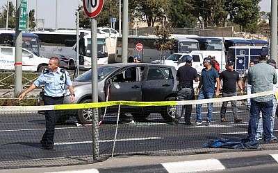 Israeli forensic policemen collect evidence from a car belonging to a victim following a terrorist attack near the Israeli police headquarters in Jerusalem on October 9, 2016. (AFP PHOTO / MENAHEM KAHANA)