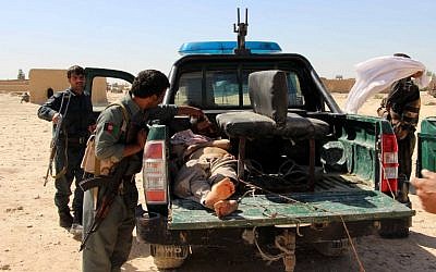 Afghan police men looks on at a body of a Taliban militant during an ongoing battle between Taliban militants and Afghan security forces in Helmand province on October 10, 2016. (photo credit: AFP/Noor Mohammad)