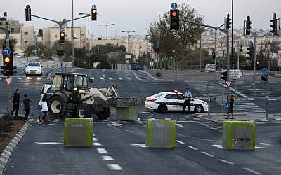 Israeli policeman stand guard as cement blocks are placed by Israeli security forces on a road linking the Arab East Jerusalem neighbourhood of Beit Hanina and West Jerusalem, on Oct. 11, 2016, ahead of Yom Kippur (AFP/Ahmad Gharabli)