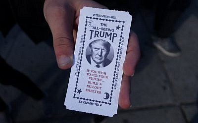 A man hold a card dispensed from the 'All-Seeing Trump', a fortune-telling fairground attraction bearing the likeness of Republican presidential candidate Donald Trump, in New York on October 12, 2016. (AFP PHOTO/William EDWARDS)
