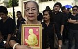 A woman holds an image of Thai King Bhumibol Adulyadej as she waits in a queue to pay her respects at the Grand Palace in Bangkok on October 14, 2016. (AFP/Munir Uz Zaman)