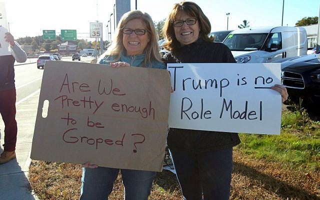 Sisters Peggy Cooke (L) and Susan Padgorski, supporters of Democratic presidential candidate Hillary Clinton, hold signs across the street from a campaign event for Republican presidential candidate Donald Trump in Portsmouth, New Hampshire on October 15, 2016. (AFP PHOTO/Mary Schwalm)