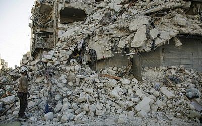 A member of the Syrian Civil Defense, known as the White Helmets, stands amid the rubble of a destroyed building during a rescue operation following reported air strikes in the rebel-held Qatarji neighborhood of the northern city of Aleppo, on October 17, 2016. (AFP PHOTO/KARAM AL-MASRI)