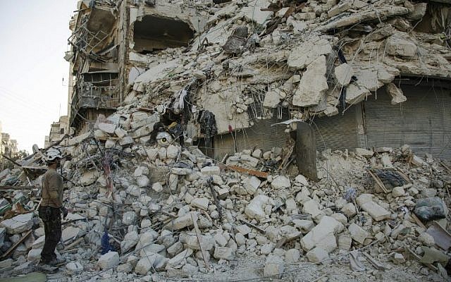 A member of the Syrian Civil Defense, known as the White Helmets, stands amid the rubble of a destroyed building during a rescue operation following reported air strikes in the rebel-held Qatarji neighborhood of the northern city of Aleppo, on October 17, 2016. (AFP PHOTO/KARAM AL-MASRI)