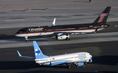 Republican presidential nominee Donald Trump's plane (TOP) passes Democratic presidential nominee Hillary Clinton's campaign plane at McCarran International Airport on October 18, 2016 in Las Vegas, Nevada, on the eve of the two candidates' third and final US presidential debate. (AFP PHOTO / Brendan Smialowski)