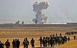 Smoke billows from an area near the Iraqi town of Nawaran, some 10km (six miles) north east of Mosul, as Iraqi Kurdish Peshmerga fighters march down a dirt road on October 20, 2016, during the ongoing operation to retake the city from the Islamic State group. (AFP/Safin Hamed)